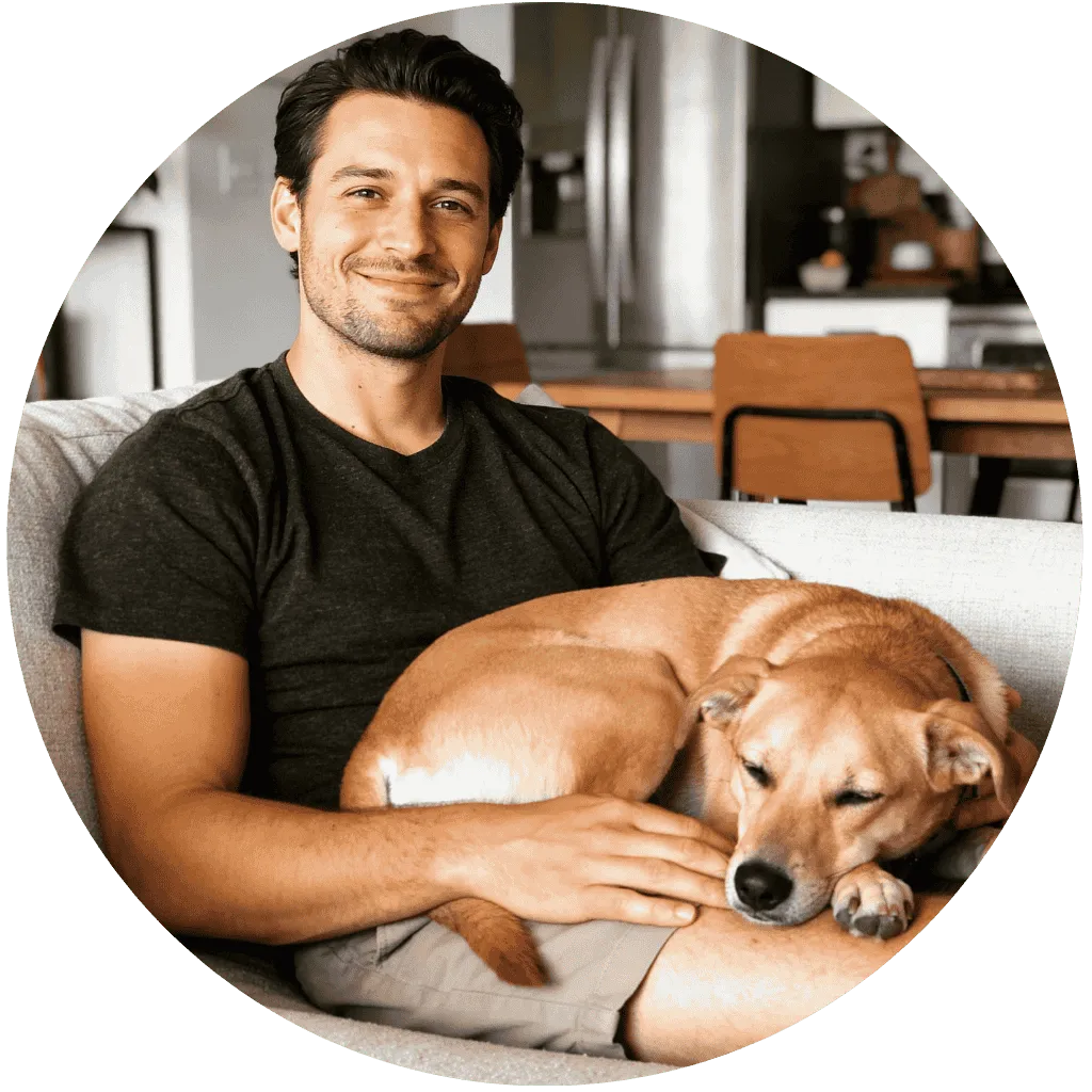 Témoignage client Pack Animaux : Lucas, trentenaire détendu, assis sur un canapé avec son chien serein et apaisé sur ses genoux, illustrant l'efficacité du CBD contre le stress animal.
